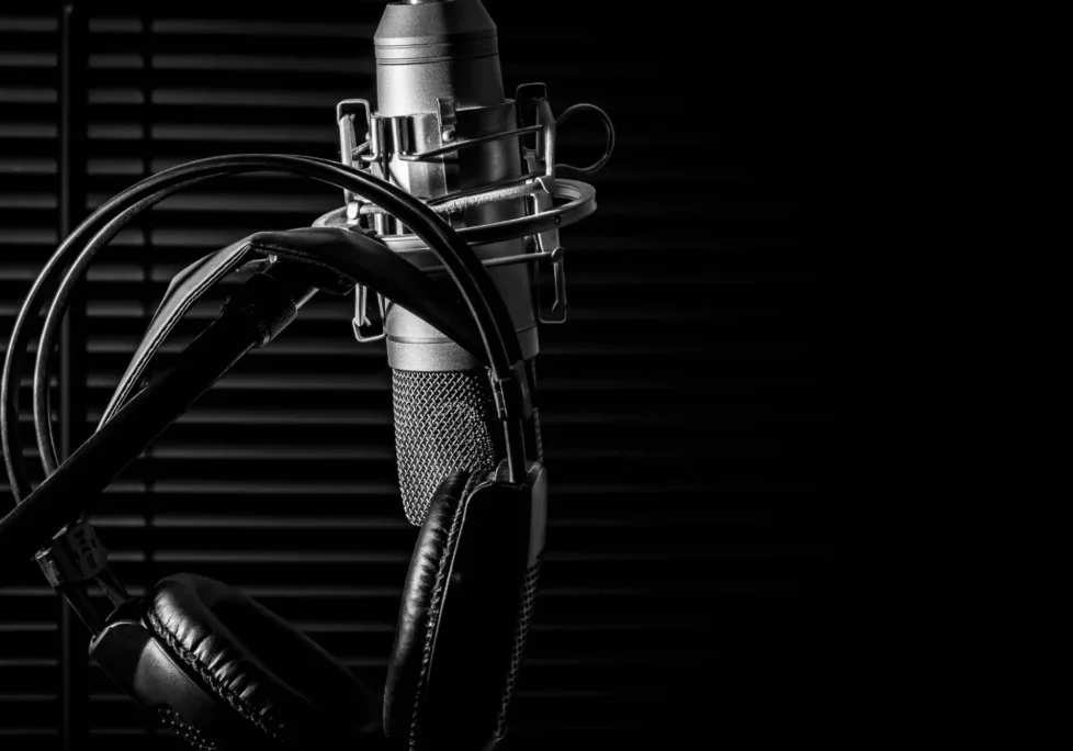 A microphone and headphones in front of a black background.